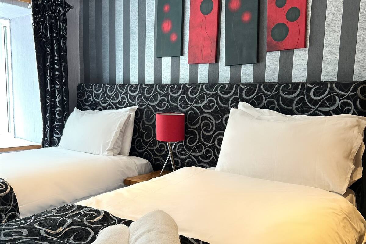 A hotel room with two beds, a patterned headboard, and artwork on the wall.