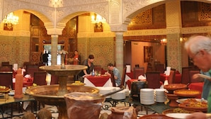 A spacious hall with ornate arches, a large chandelier, and a central fountain. Tables are set with plates and cutlery, suggesting a dining area. - Hotel Imperial Plaza (Marrakech)