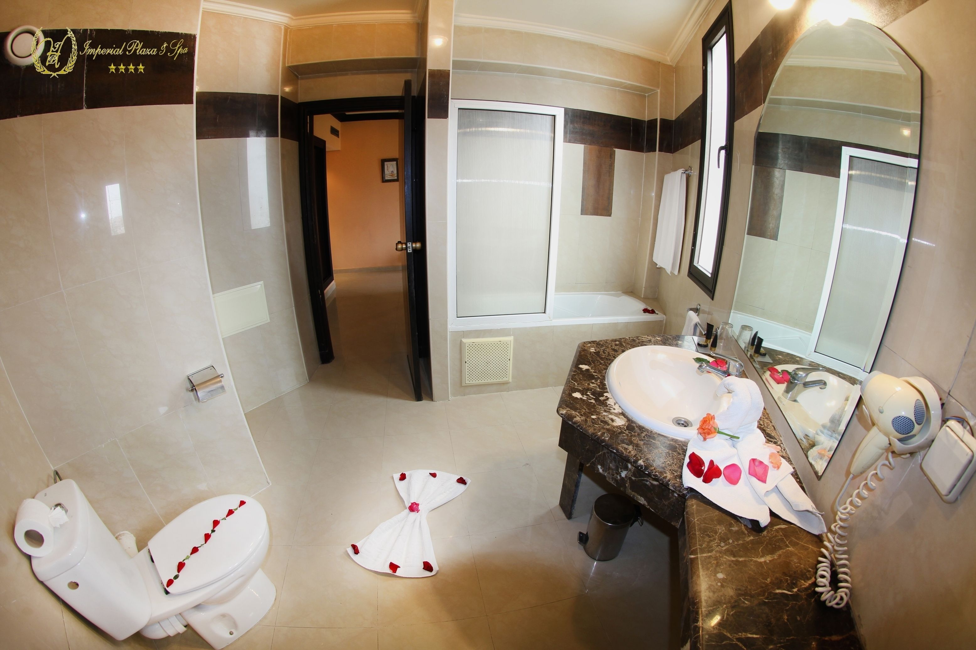 A bathroom with a toilet, sink, and large mirror.
