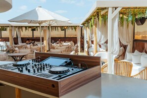 A DJ booth with a control panel, surrounded by outdoor seating with umbrellas and cushions. - Hotel Imperial Plaza (Marrakech)