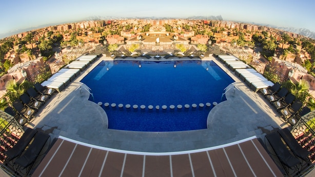 A large swimming pool surrounded by lounge chairs and a view of a cityscape. - Hotel Imperial Plaza (Marrakech)