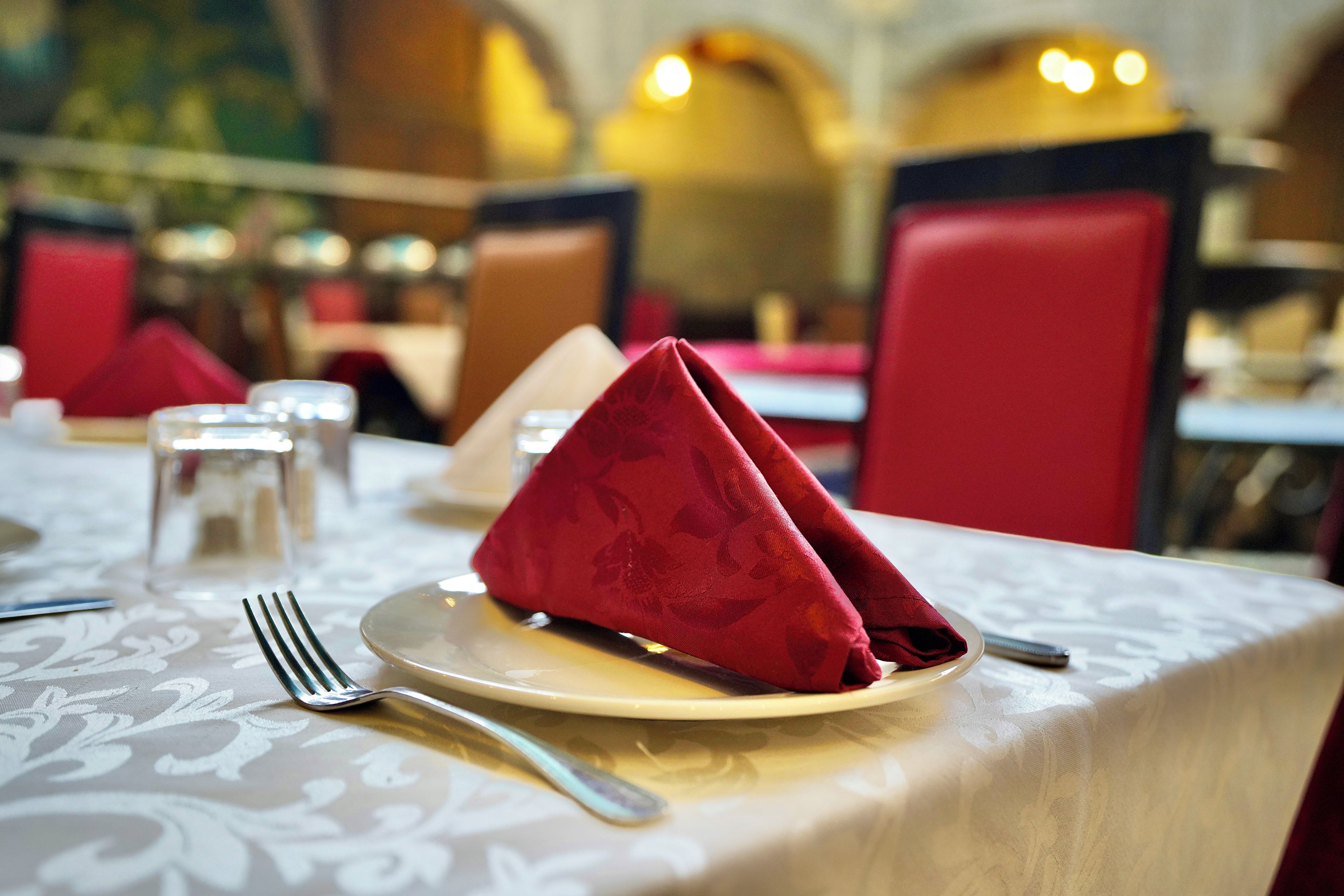A dining table with a folded napkin, a fork, and a glass of water.