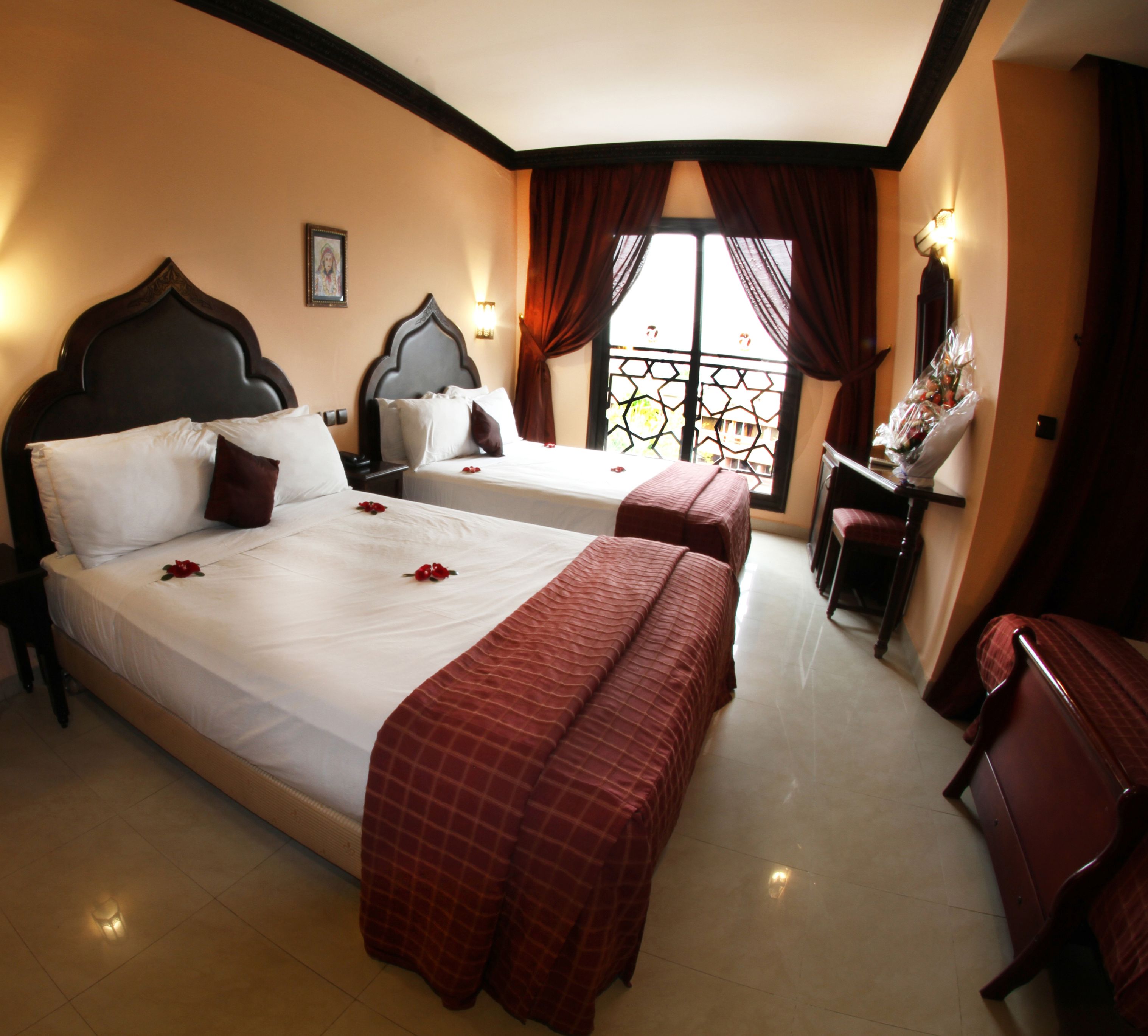 Une chambre d’hôtel avec deux lits, un bureau et une fenêtre avec des rideaux.