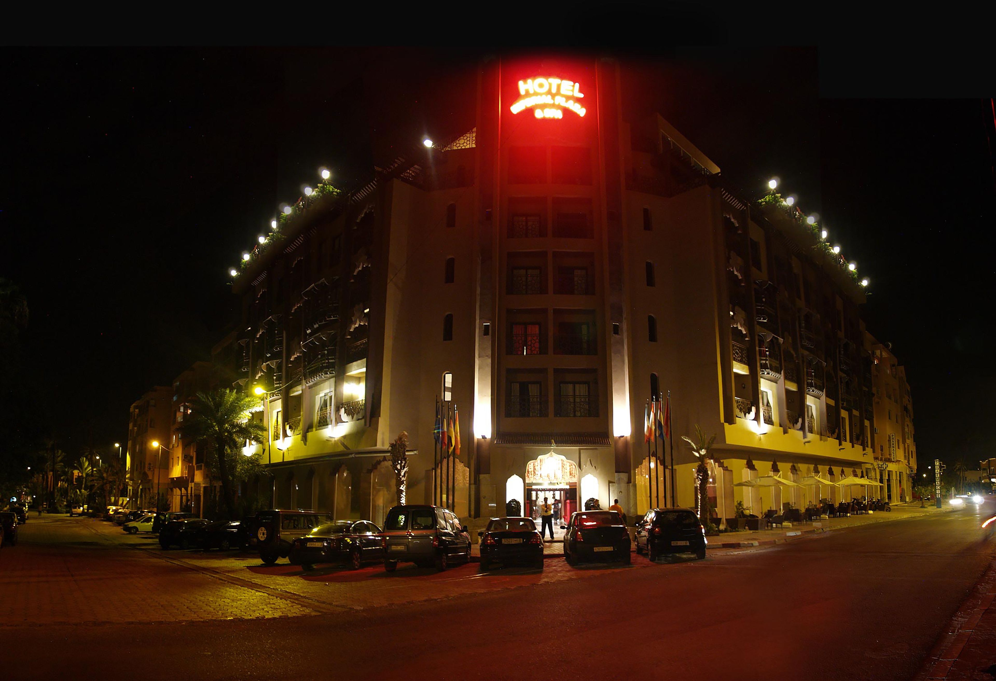 A hotel with a prominent red sign, multiple floors, and a well-lit entrance.