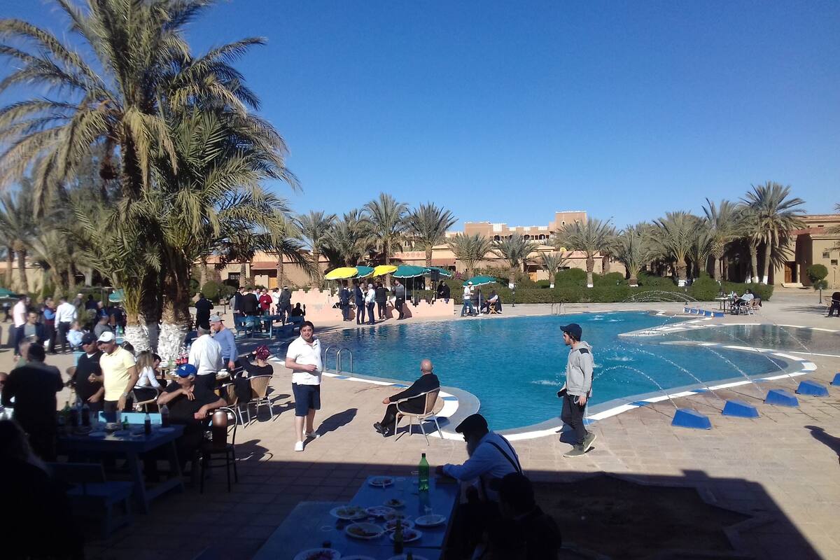 A poolside area with palm trees, outdoor seating, and a clear blue sky.
