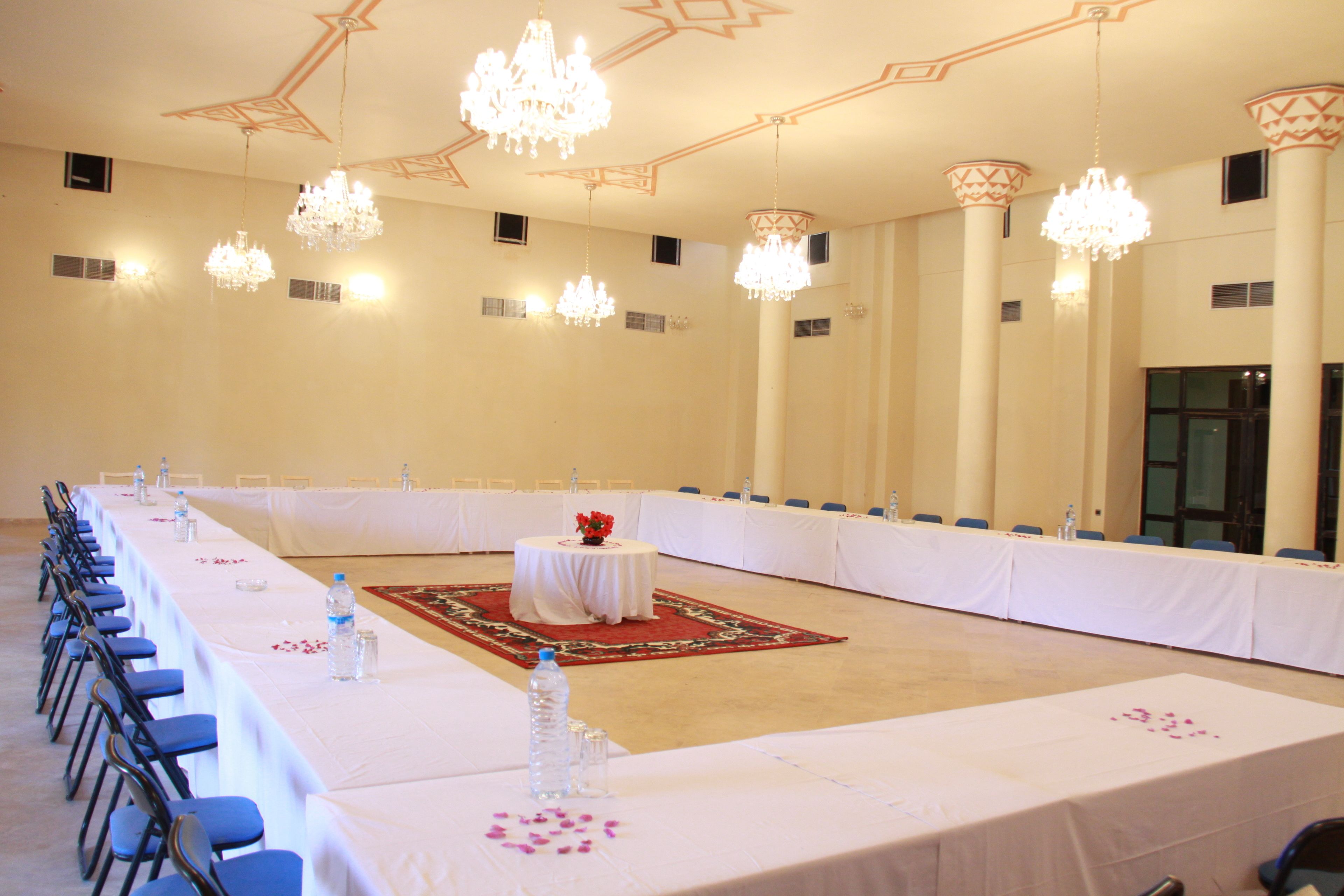 A large conference room with a long table, chairs, and chandeliers.
