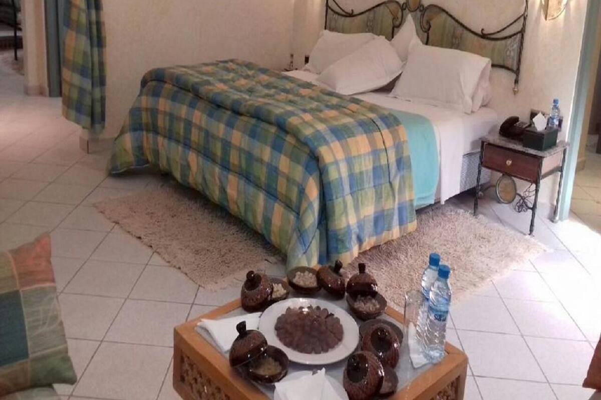 A bedroom with a bed, bedside table, and a tray with food items.