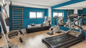 A gym with exercise equipment, a treadmill, and a mirrored wall. - Welcome Hotel Legnano (Legnano)