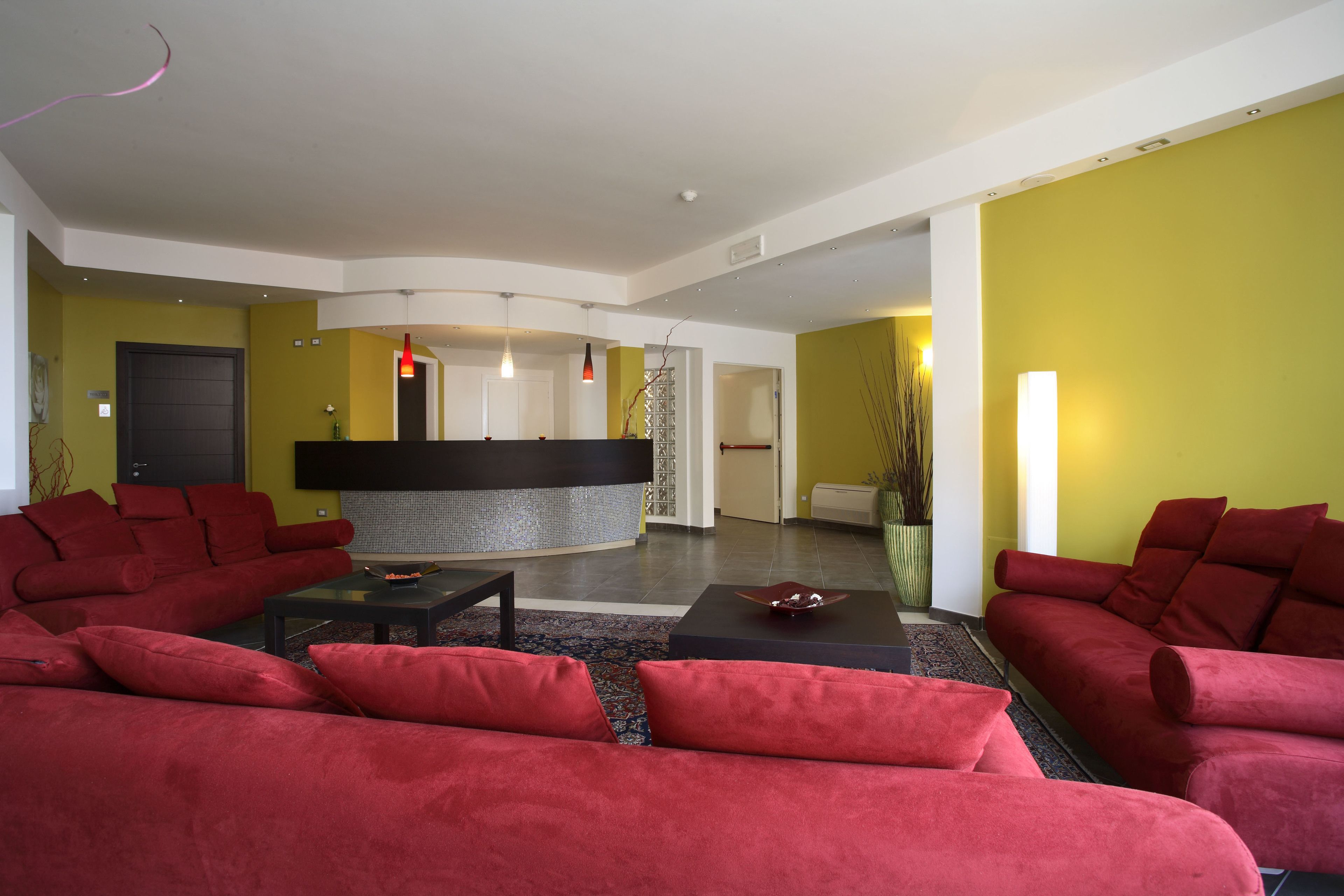 A modern living room with red sofas, a black coffee table, and a central black fireplace.