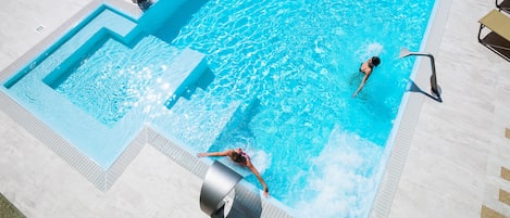 Une piscine avec un plongeoir et des chaises longues.