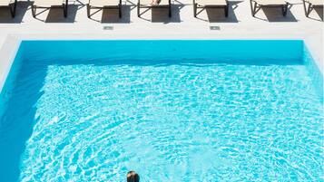 Una piscina con lettini e una persona a nuoto.