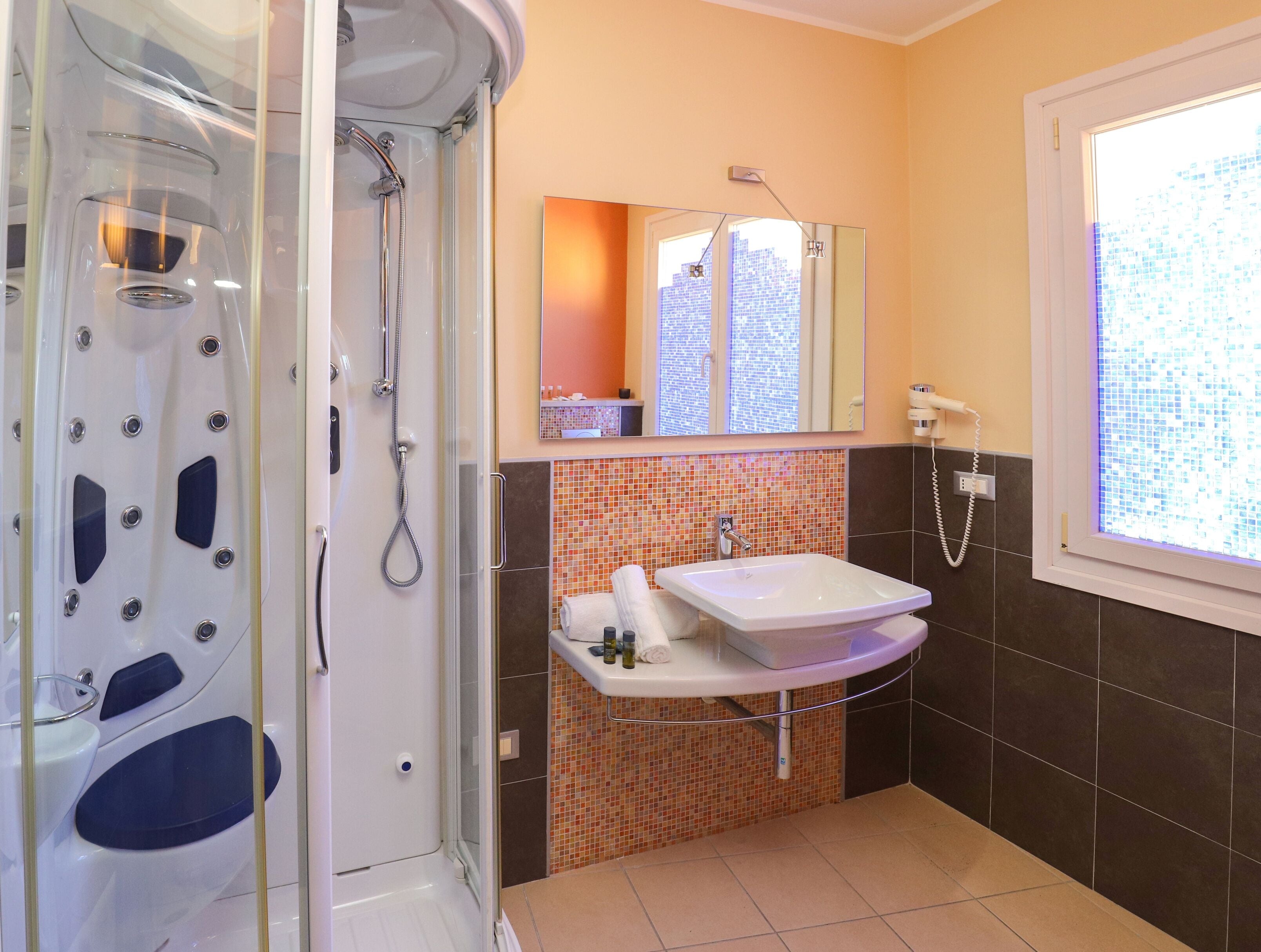 Un baño con ducha separada por mampara de vidrio, lavabo y espejo sobre él.