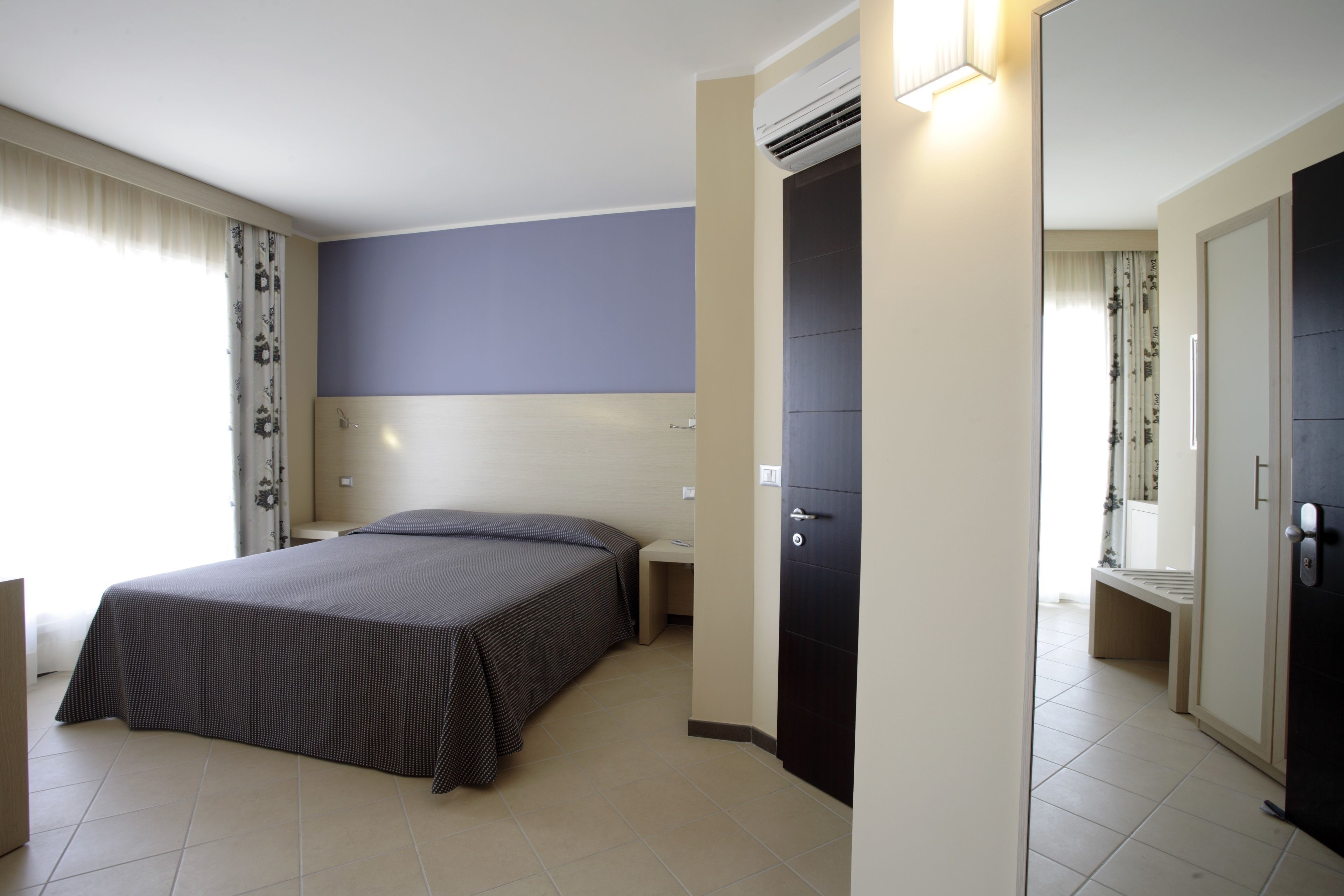 Une chambre d’hôtel avec un lit, une table de chevet et une armoire.