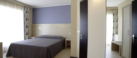 Habitación de hotel con cama, mesita de noche y armario.