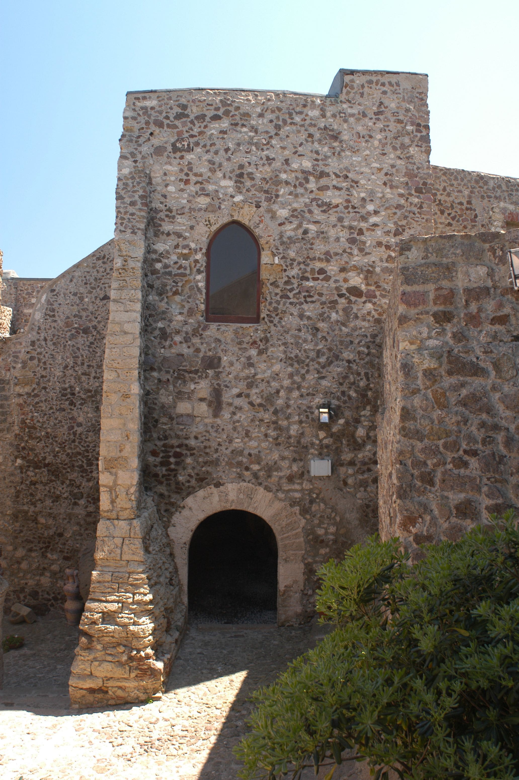 A stone building with a central arched entrance and a rectangular window above it.