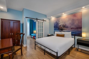 A hotel room with a bed, a desk, a chair, a wardrobe, and a large painting of a sailboat on the wall. - Hotel Brossard, an Ascend Collection Hotel (Brossard)