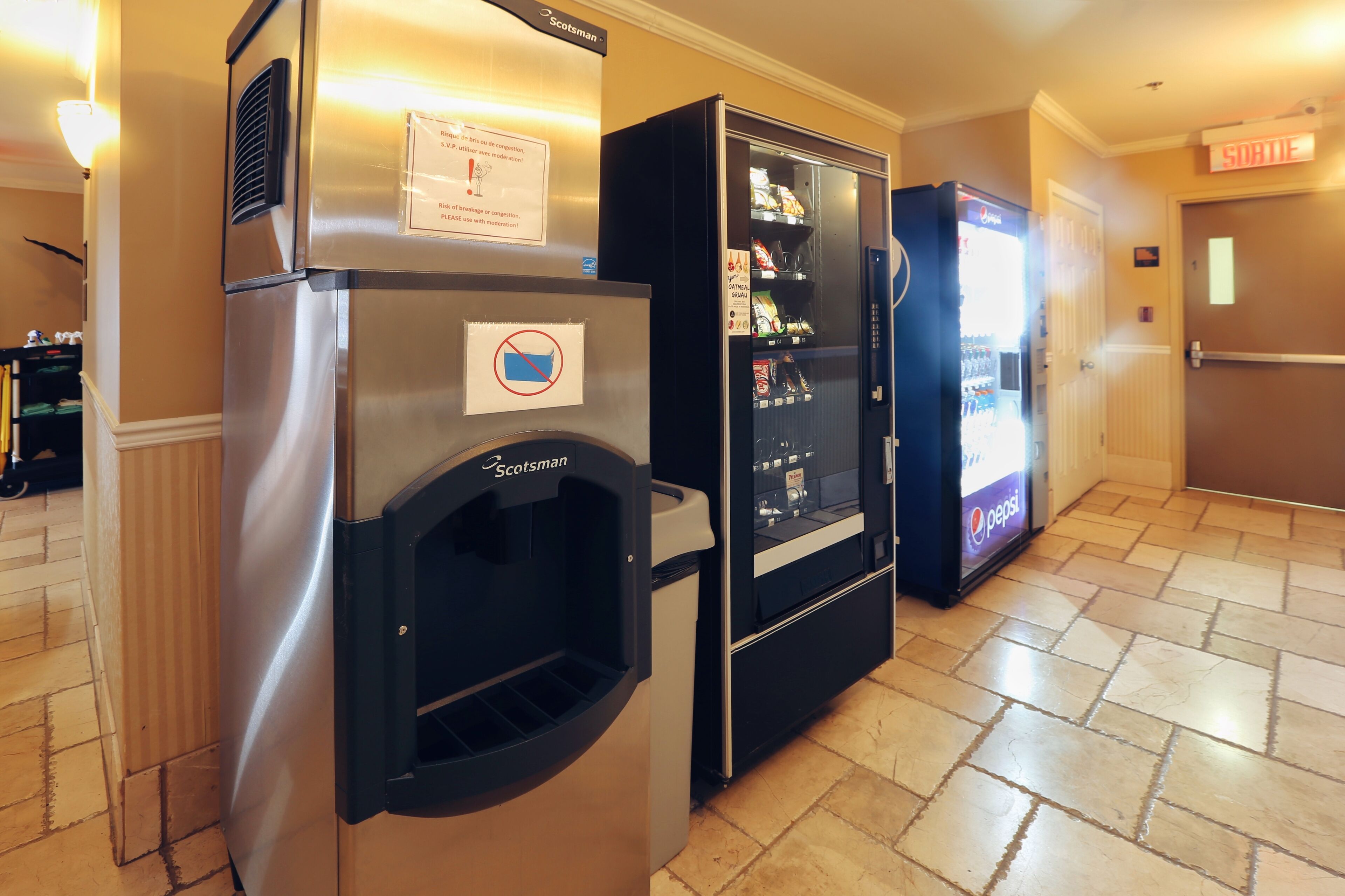 A hotel room with a minibar, a refrigerator, and a vending machine.