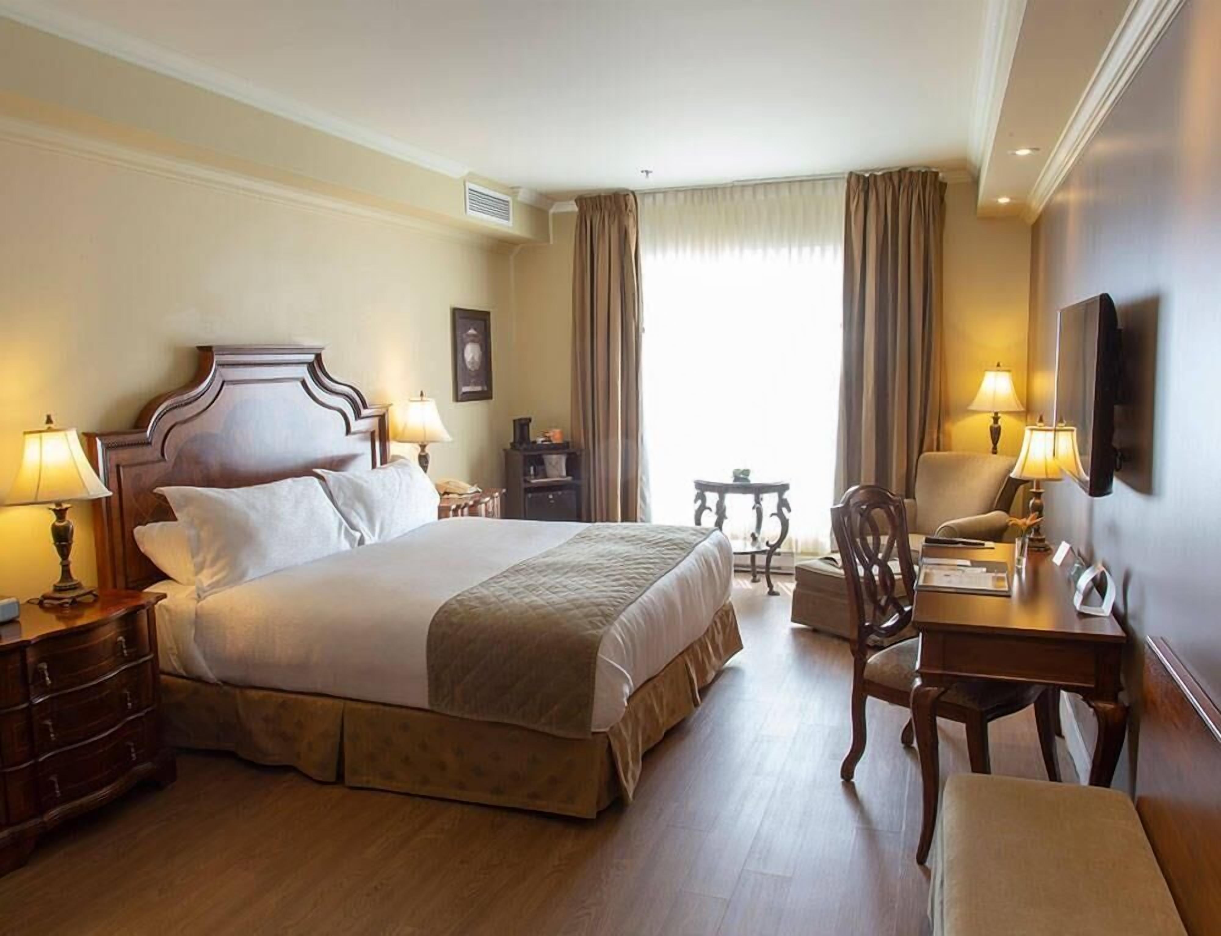 Una habitación de hotel con cama, mesitas de noche, un escritorio y una silla.