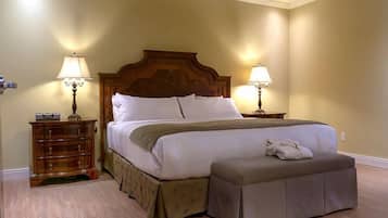 Una habitación de hotel con una cama grande, dos mesitas de noche con lámparas, un aparador de madera y un banco.