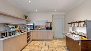 Una cocina moderna con electrodomésticos integrados, un espacio para café y diversos alimentos.