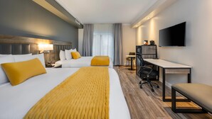 A hotel room with a bed, a desk, a chair, a TV, and a window with curtains. - Hotel Brossard, an Ascend Collection Hotel (Brossard)