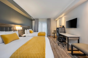 Una habitación de hotel con cama, escritorio, silla, televisión y ventana con cortinas.