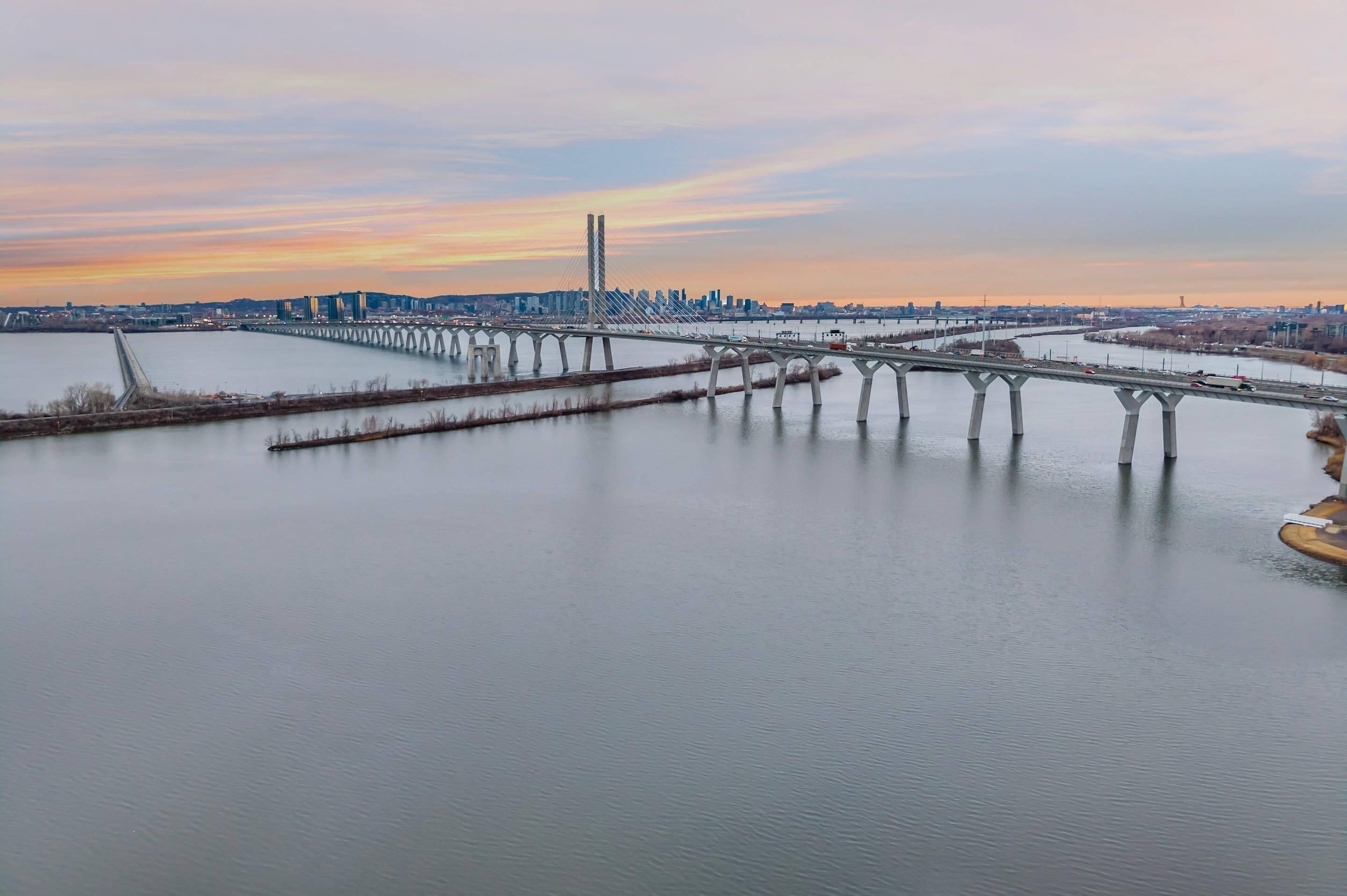 Eine Brücke über einem Fluss, im Hintergrund die Skyline einer Stadt.