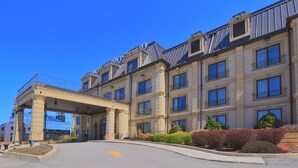 A large, multi-story hotel with a classic architectural style, featuring a prominent entrance with a covered walkway and a landscaped garden area. - Hotel Brossard, an Ascend Collection Hotel (Brossard)