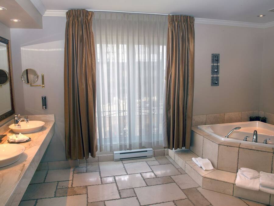 A bathroom with two sinks, a bathtub, and a large mirror.