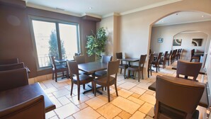 A restaurant with multiple tables and chairs, large windows, and a potted plant. - Hotel Brossard, an Ascend Collection Hotel (Brossard)
