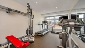 Ein Fitnessraum mit Laufband, Kraftmaschine und einer roten Hantelbank.