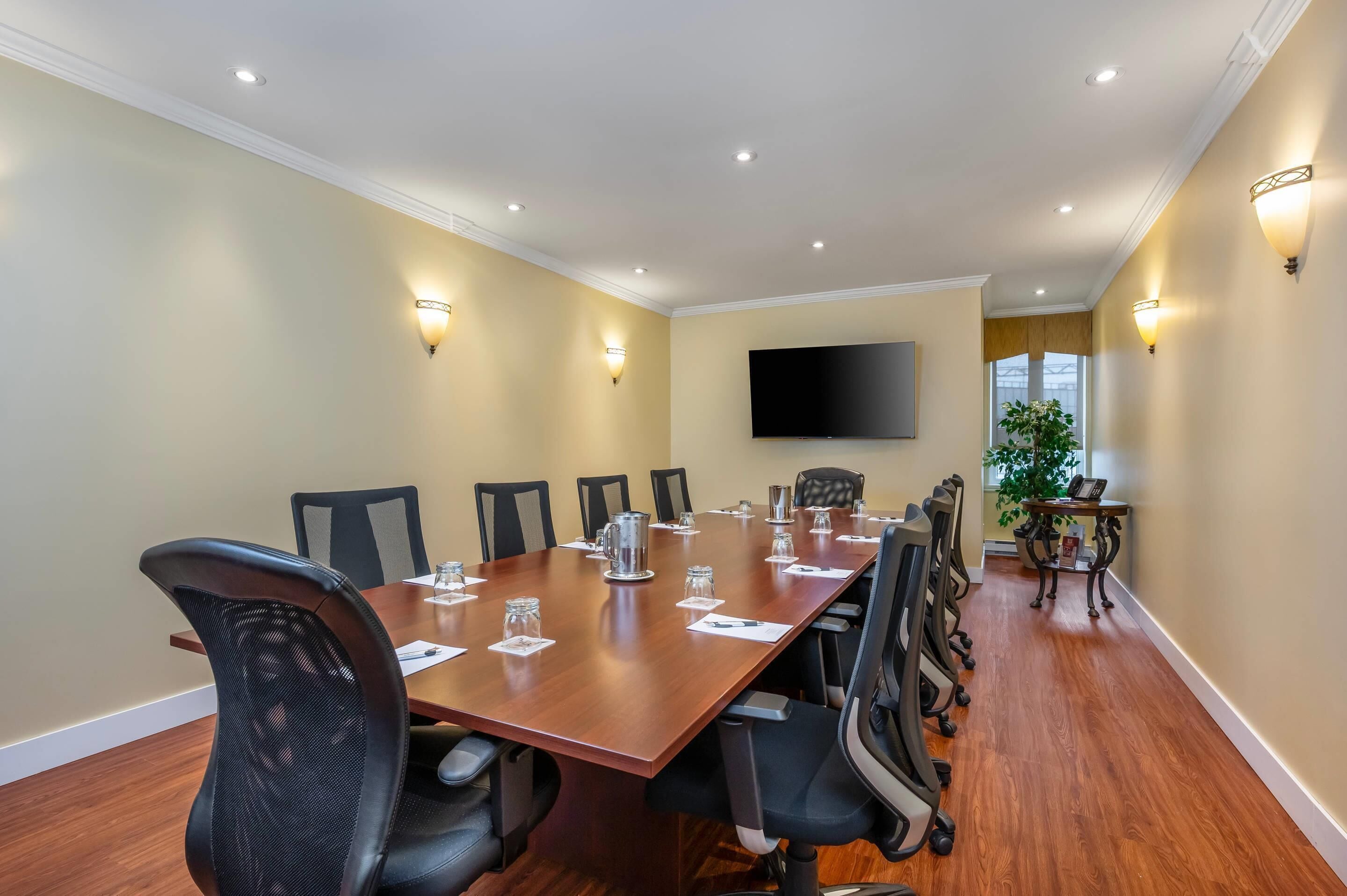 A conference room with a long table, chairs, and wall-mounted lights.