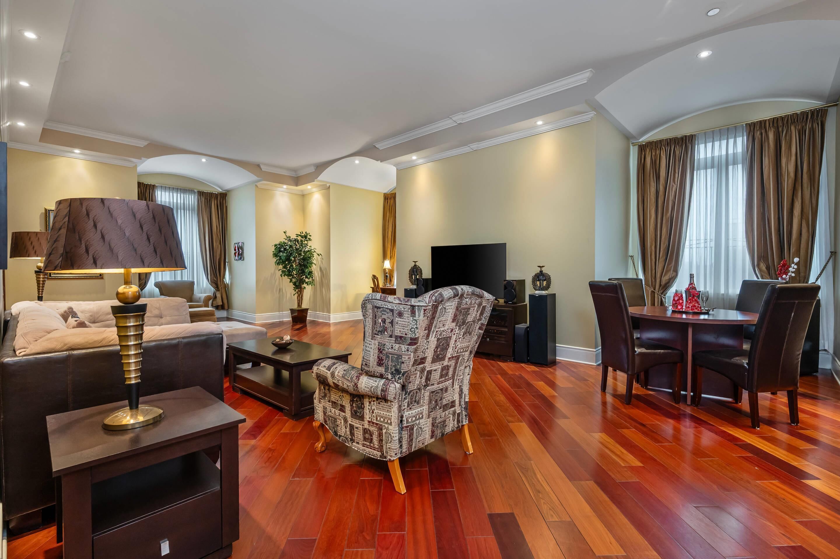 A living room with a sofa, armchair, coffee table, TV, and dining table.