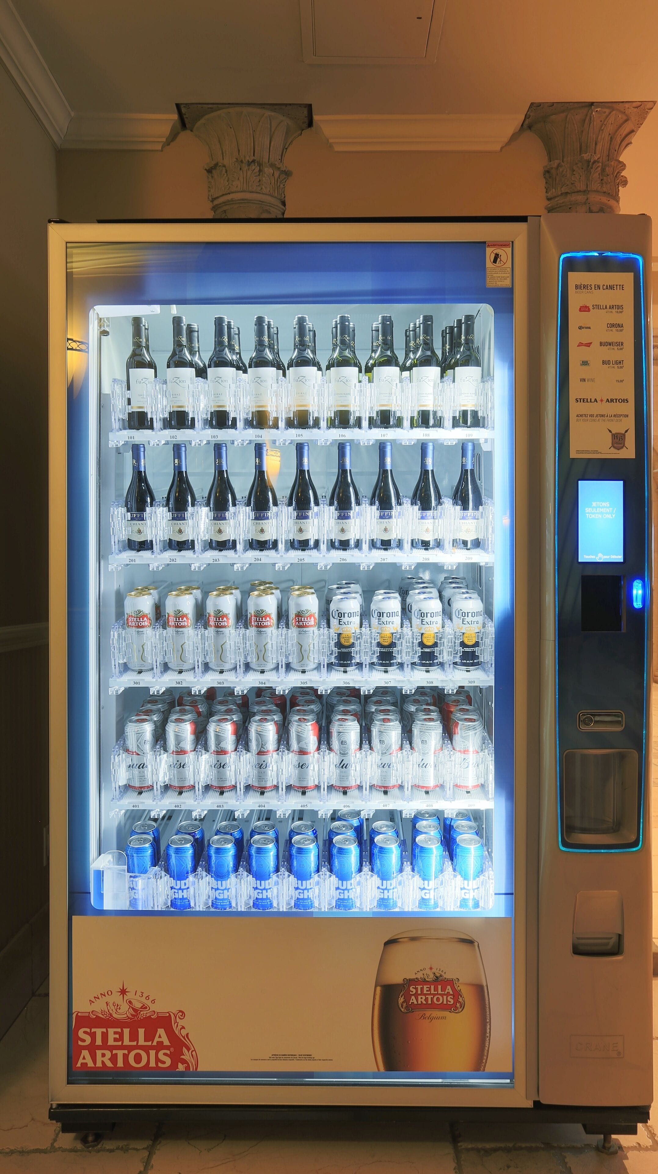A vending machine stocked with various beverages including Stella Artois beer and Corona beer.