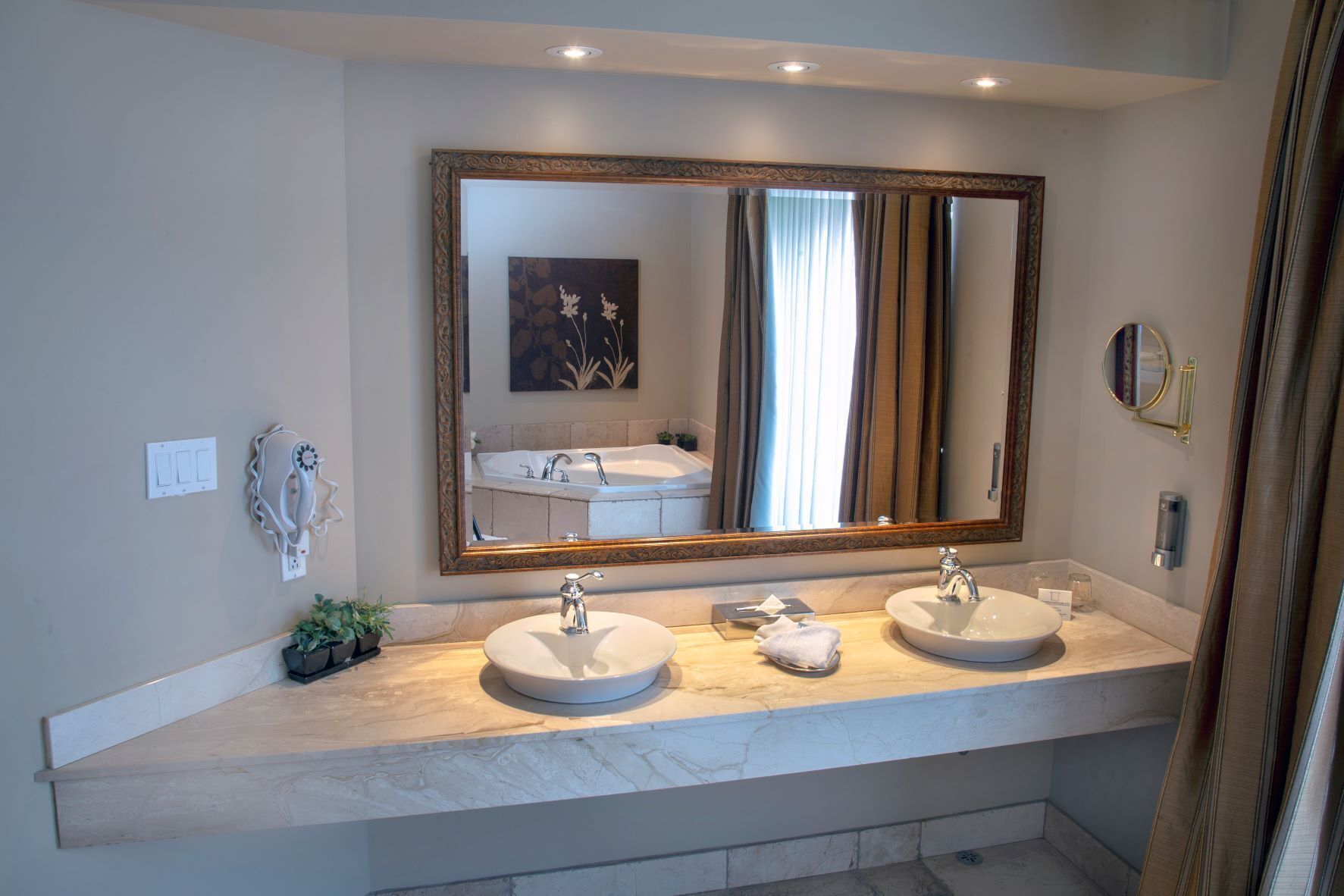 Un baño con dos lavabos, un espejo grande y una planta en maceta.