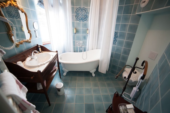 A bathroom with a freestanding bathtub, a wooden vanity with a sink, and a toilet. - Château du Colombier (Saint-Malo)