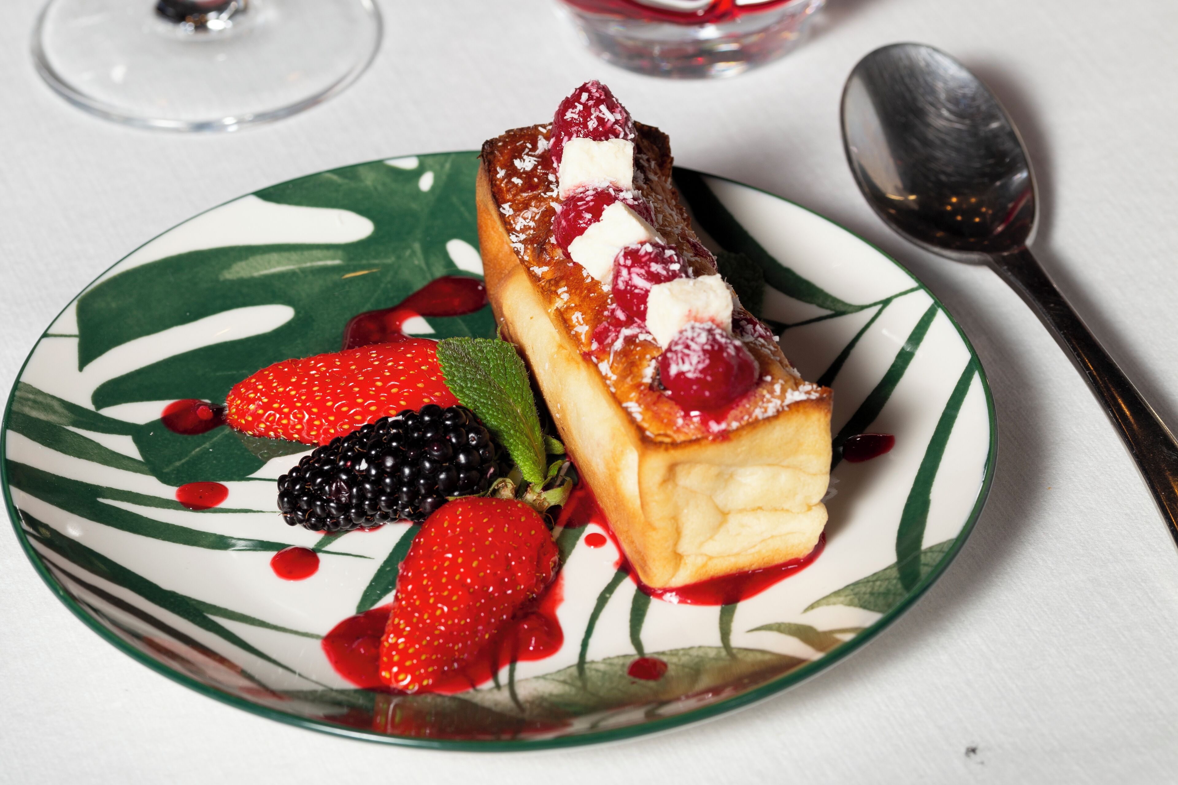 A dessert plate with a pastry, strawberries, blackberries, and mint leaves.