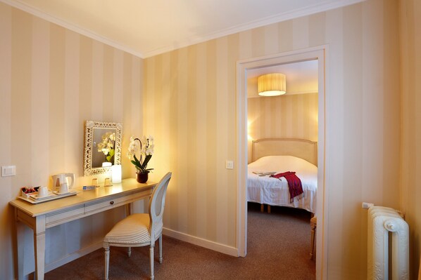 A hotel room with a bed, a desk with a chair, a mirror, and a bedside table with a lamp. - Hostellerie des Trois Pigeons (Paray-le-Monial)