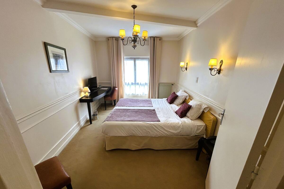 Une chambre d’hôtel équipée d’un lit, d’un bureau, d’une chaise et offrant une vue sur l’extérieur.