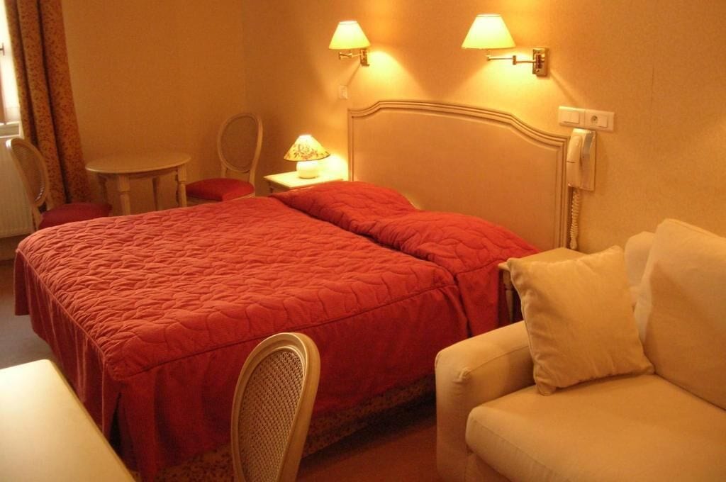 Ein Hotelzimmer mit einem großen Bett, einem Nachttisch mit Lampe, einem Sessel und einem Sofa.
