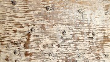 Primer plano de una superficie de madera desgastada con un anillo metálico.