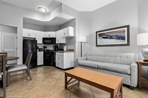 Un espacio habitable compacto con kitchenette, un sofá, una mesa de comedor y una lámpara.