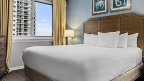 A hotel room with a large bed, a dresser, a nightstand, two wall-mounted lamps, and a window with blinds. - Club Wyndham at Majestic Sun (Miramar Beach)
