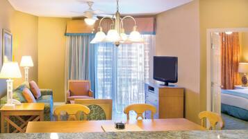 A hotel room with a dining area, a television, a bed, and a window with curtains.