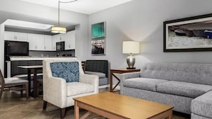 A modern living room with a grey sofa, a wooden coffee table, and a dining area with a kitchen in the background. - Club Wyndham at Majestic Sun (Miramar Beach)