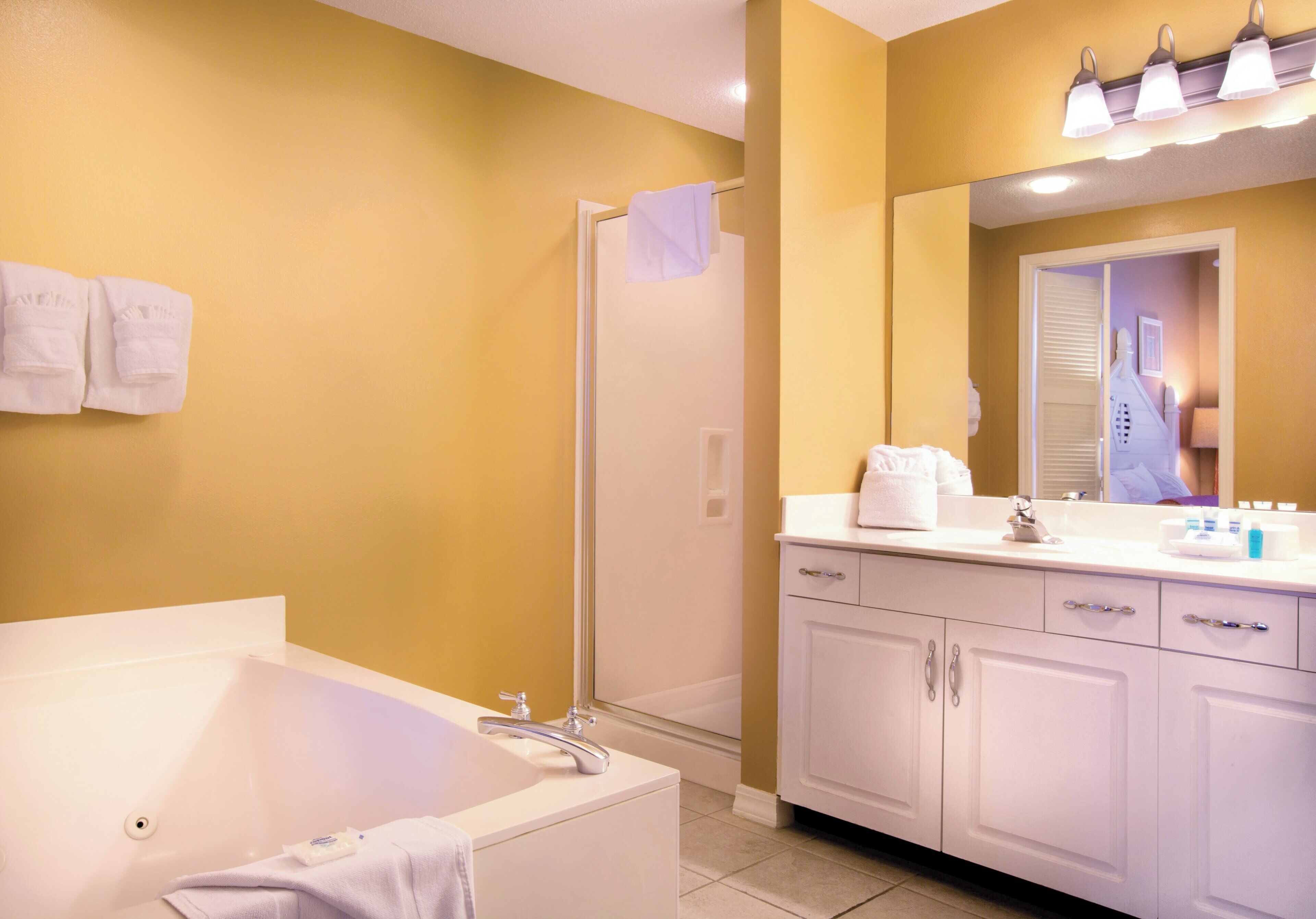 A bathroom with a bathtub, a shower, and a vanity with a mirror.