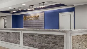 A reception area with a blue accent wall, a reception desk, and a textured wall panel. - Club Wyndham at Majestic Sun (Miramar Beach)