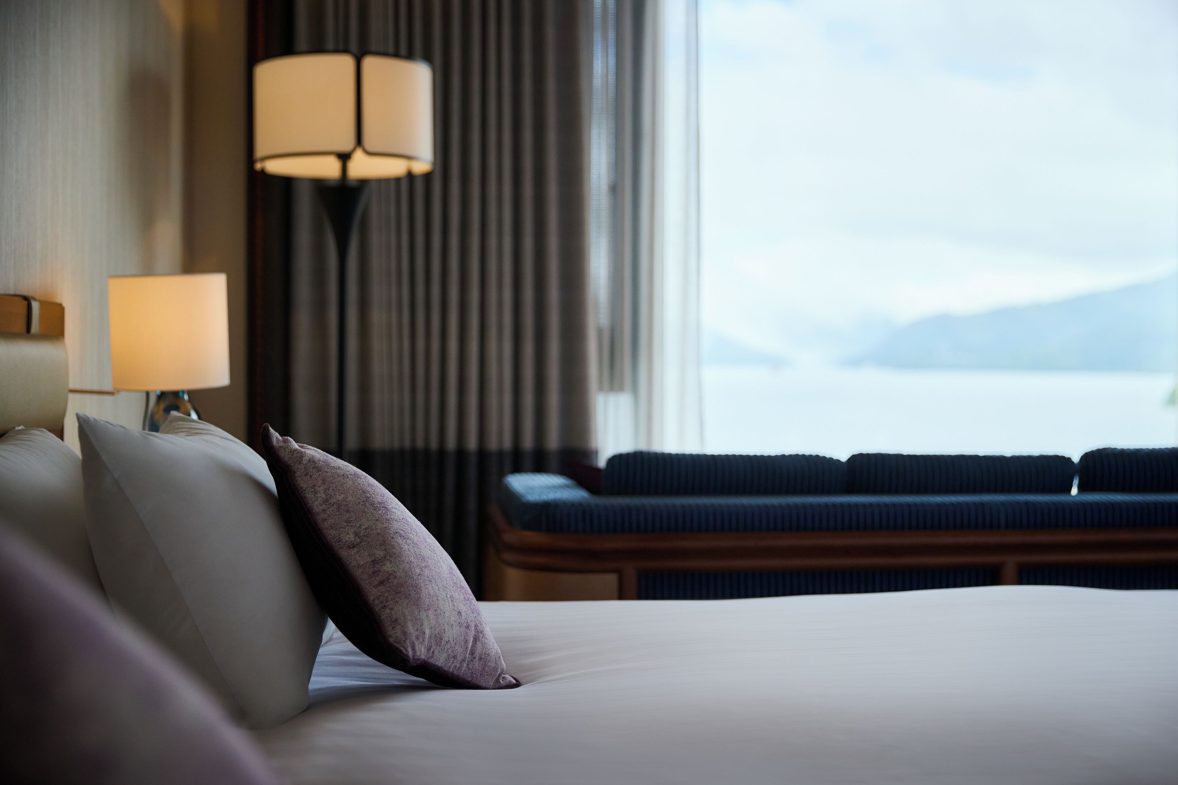 Une chambre d’hôtel avec un lit, une lampe, un canapé et une vue sur la mer.