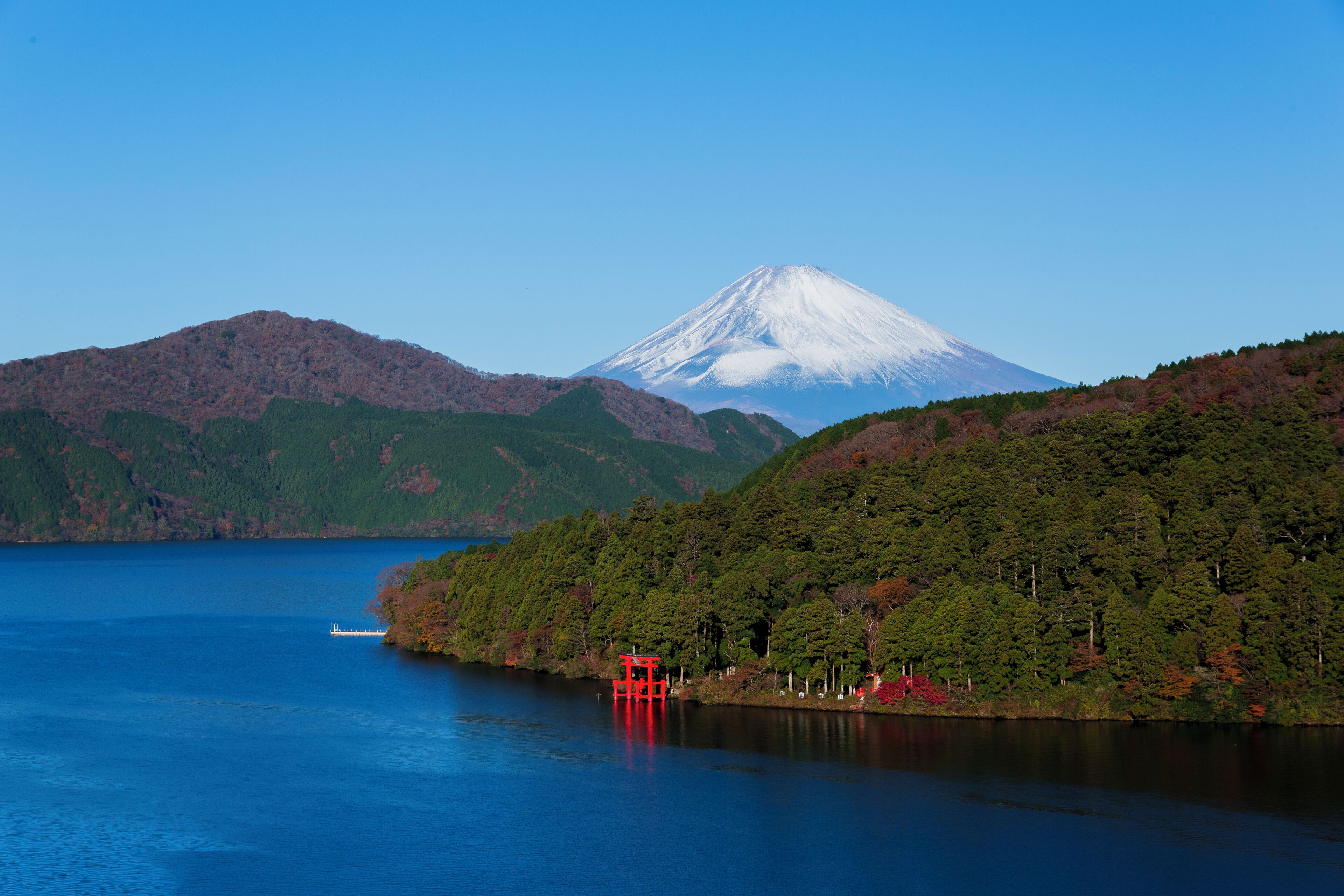 A lake with a mountain in the background and a red structure on the shore.