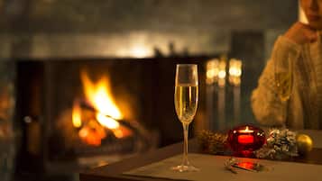 A glass of champagne on a table with a fireplace in the background.